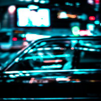 ネオンを反射するタクシーが行き交う夜景の都市風景の写真