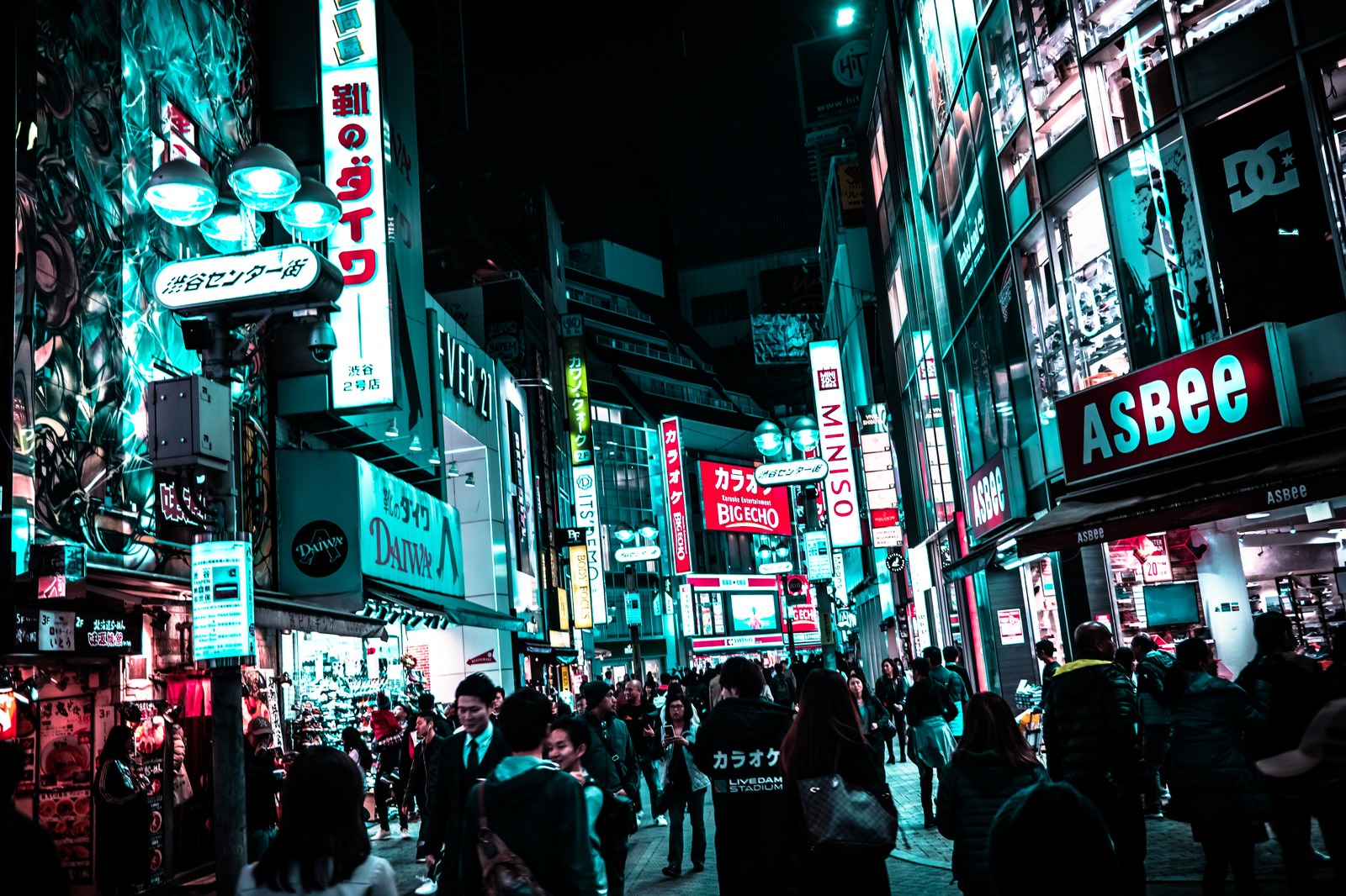夜の渋谷センター街でネオンサインが光る中を歩く通行人たち
