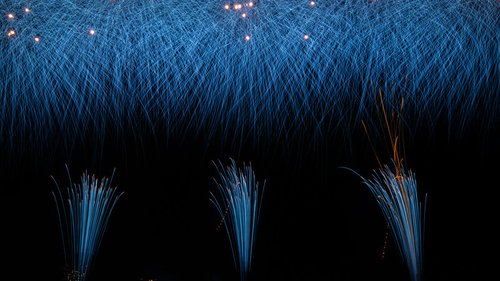 夜空を彩る青い光、降り注ぐ打上げ花火、夏の夜間イベント