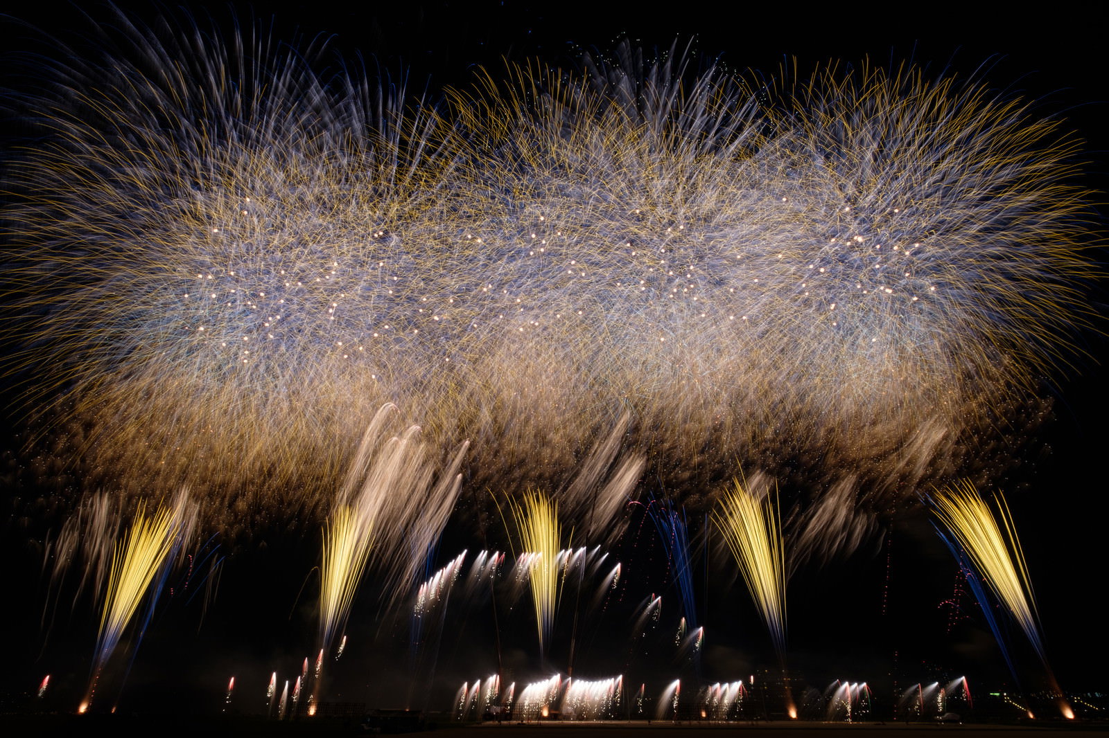 夜空に大きく炸裂する打上花火と連続する花火の光跡