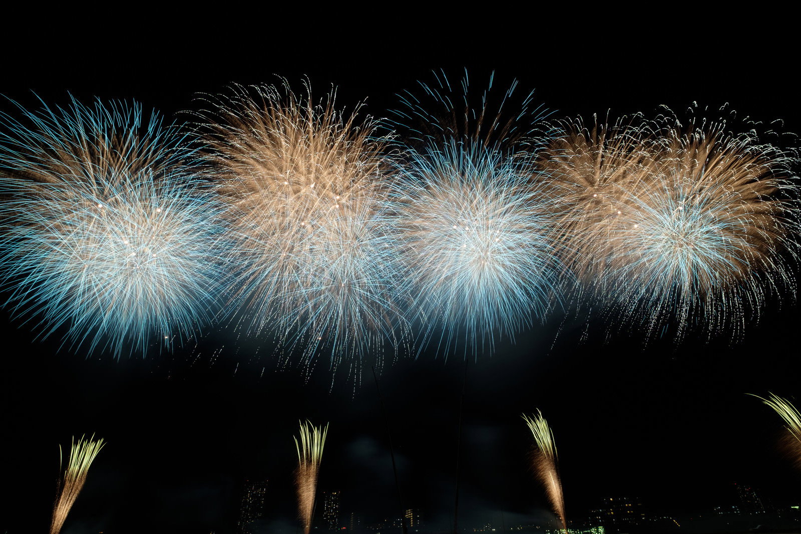 夏の夜空に連続して打ち上がる青と金色の美しい花火