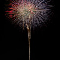 夜空に高く打ち上げる大玉花火が放つ光の軌跡の写真