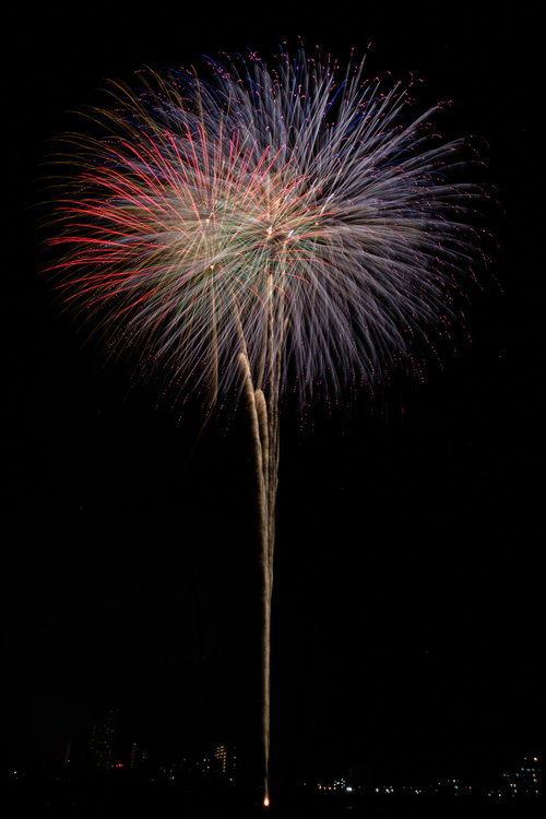 夜空に高く打ち上げる大玉花火が放つ光の軌跡