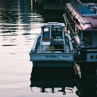 夕暮れ時の神田川に係留された釣り船と屋形船の写真