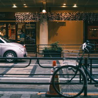 夜の街角に停められた白い車と自転車の路上駐車の写真