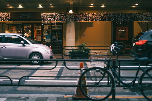 夜の街角に停められた白い車と自転車の路上駐車