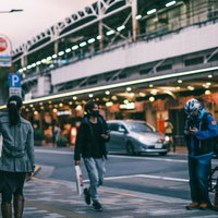 夕暮れ時の駅前歩道を行き交う通行人たちの日常風景の写真