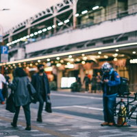 夕暮れ時の街角の歩道を行き交う通行人たちの写真