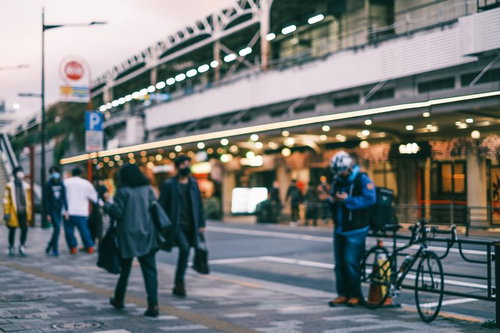 夕暮れ時の街角の歩道を行き交う通行人たち