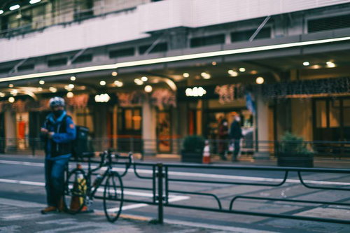 自転車を降りた街角の配達員が荷物を持って配達準備をしている様子