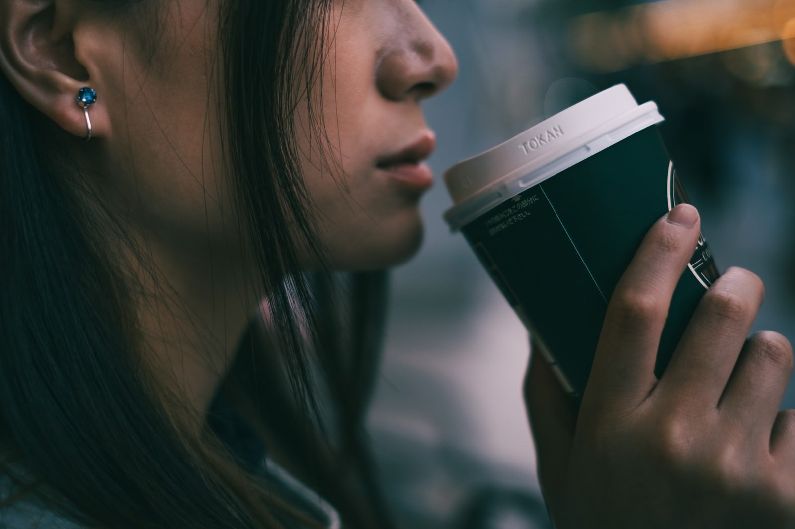 白いコーヒーカップを口元に近づけて飲もうとしている女性
