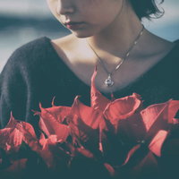 赤いポインセチアを持つ虚ろな女性の写真