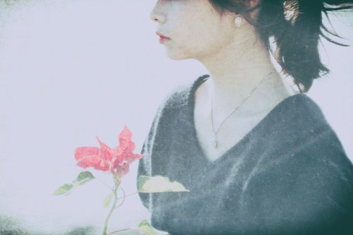 ピンクの花を握るセンチメンタルな気分の女性