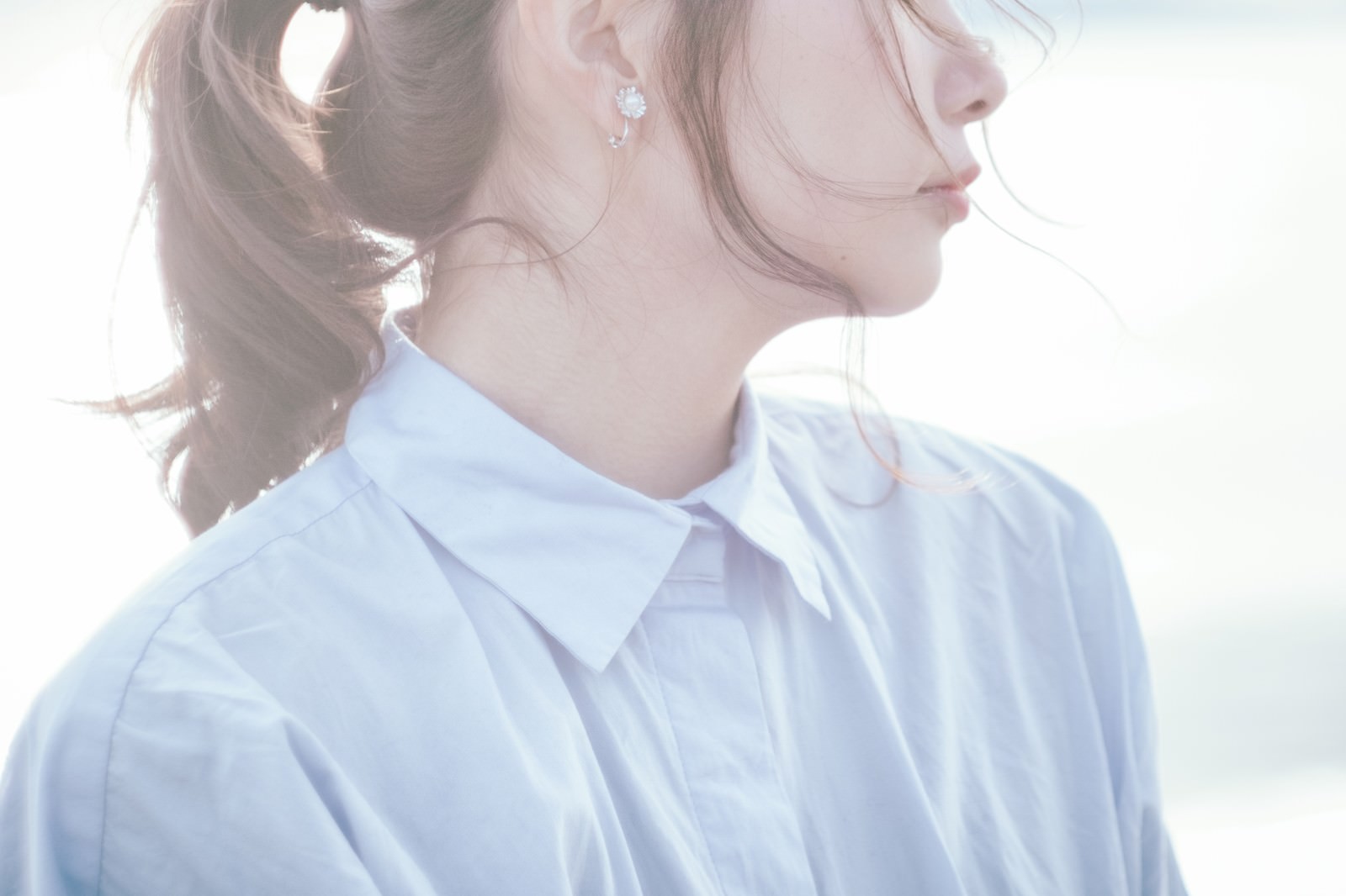 水色のシャツを着てポニーテールを揺らす若い女性の横顔