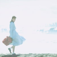 海面の反射と彼女が歩く波打ち際の夏のデート風景の写真