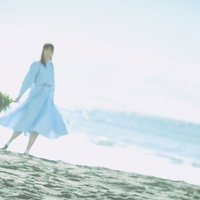 爽やかな朝の海辺で白いワンピースを着た女性が花束を持つの写真