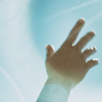 青空と太陽に向かって伸ばす手のシルエットの写真