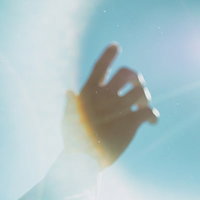 逆光で太陽に向けて伸ばす手のひらの写真