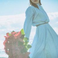 よく晴れた海辺でポインセチアの花束を持つ女性の写真