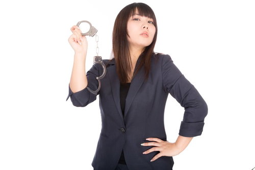 手錠を掲げる高圧的な女性弁護士、法廷での厳格な態度を表現