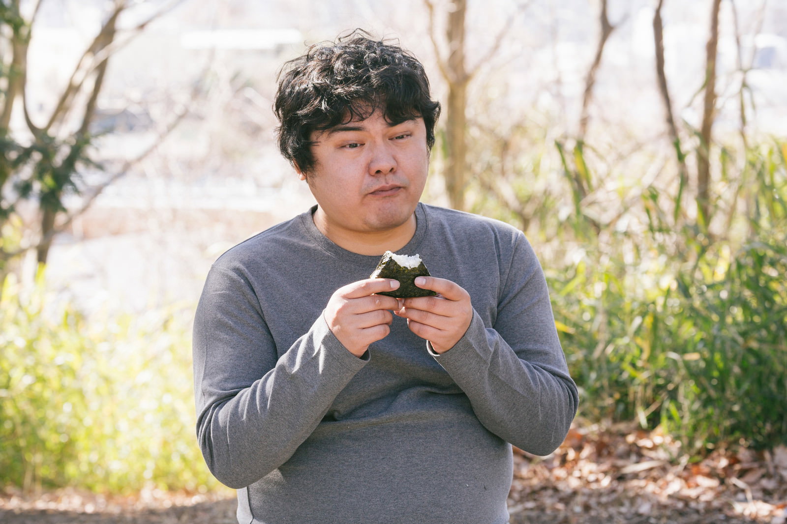 ダイエット中の男性がおにぎり1個を手に持つ［モデル：段田隼人］