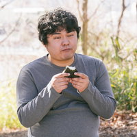 ダイエット中の男性が屋外でおにぎり1個を握るの写真