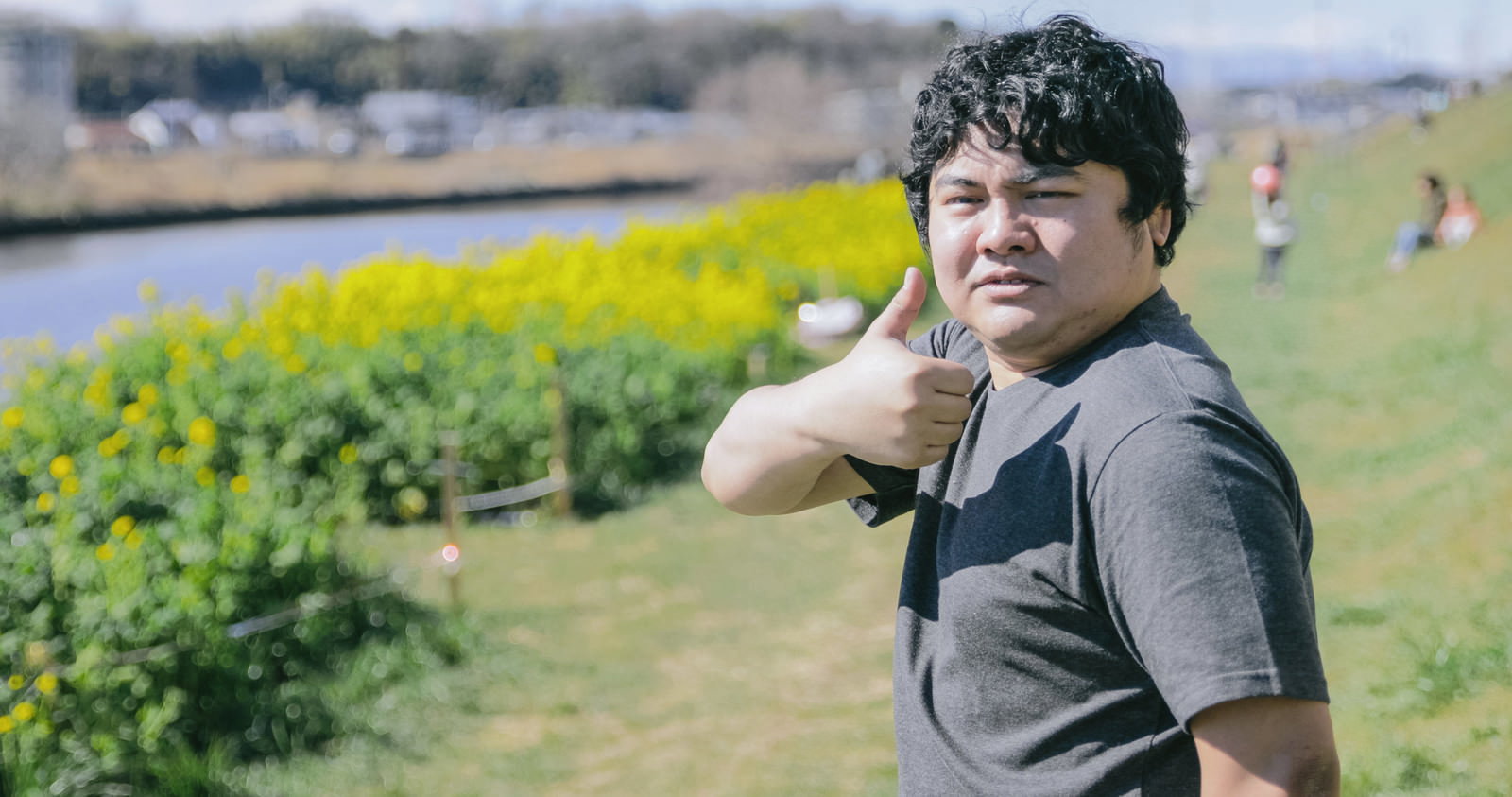 菜の花畑でサムズアップする男性［モデル：段田隼人］