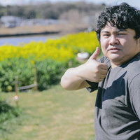 菜の花畑でサムズアップする男性のポートレートの写真