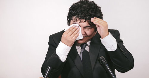 記者会見で涙を流しながら謝罪する男性ビジネスマン