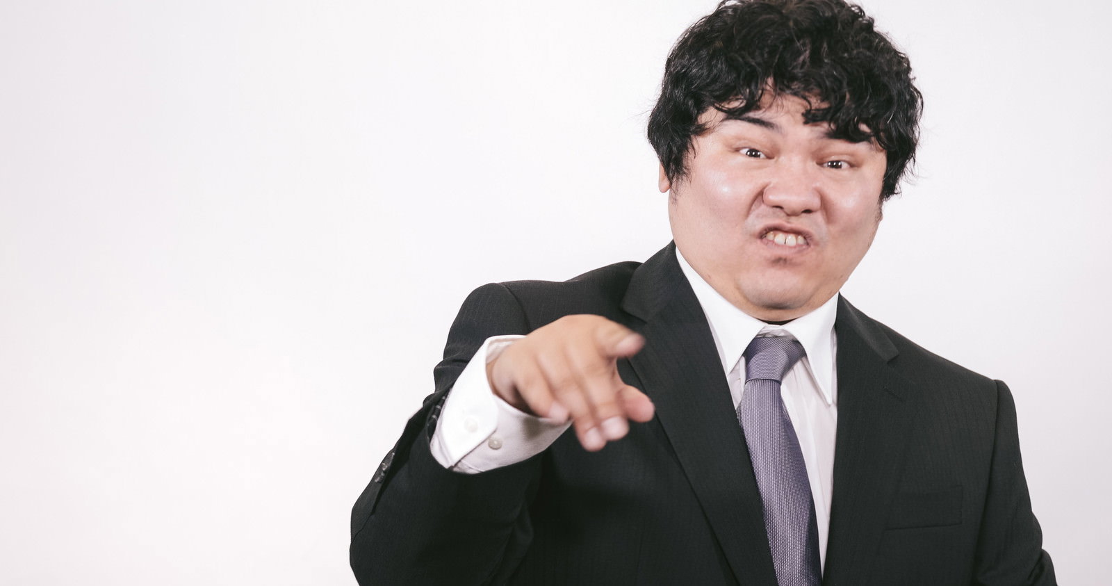 黒いスーツの男性が指を差しながら怒った表情で叱責している［モデル：段田隼人］
