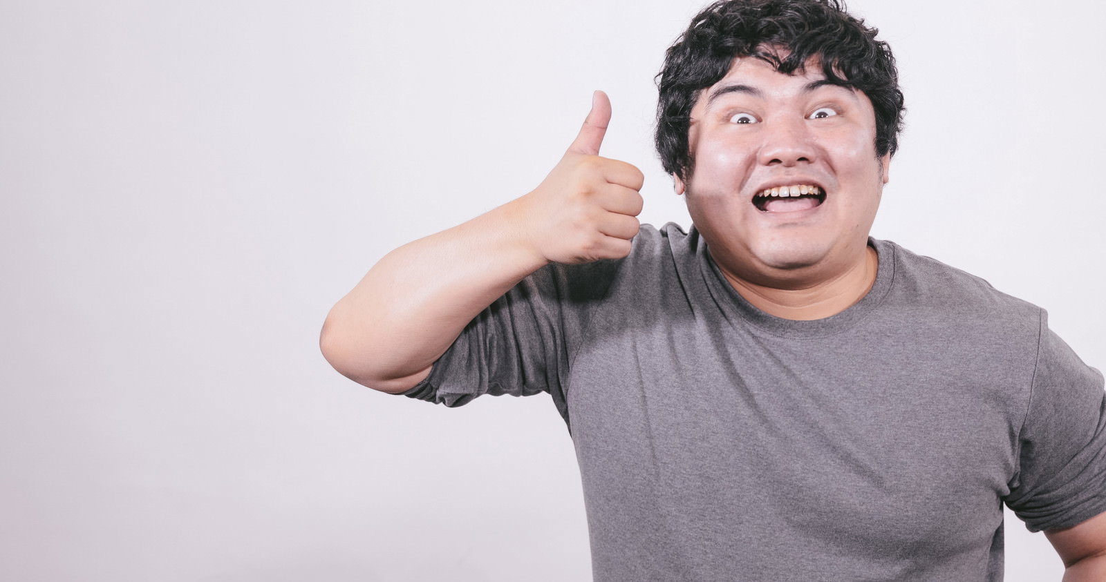 サムズアップして大きく笑顔の男性［モデル：段田隼人］