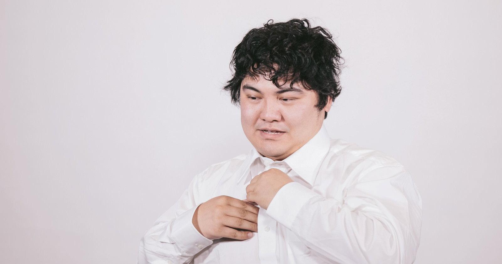 袖口を直す疲れたビジネスマン［モデル：段田隼人］
