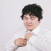 ワイシャツを脱いで疲労を見せるビジネスマンの写真