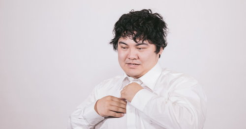 ワイシャツを脱いで疲労を見せるビジネスマン