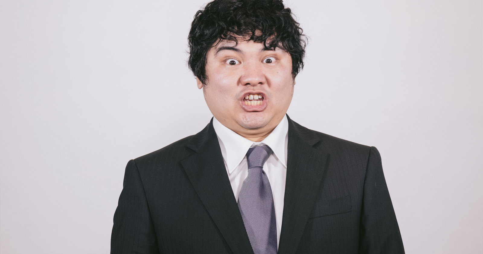 スーツネクタイ姿の男性が驚いた顔で正面を向いている