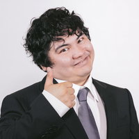 黒いスーツの男性が親指を立てるサムズアップポーズの写真