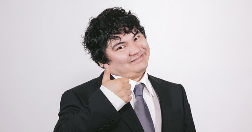 黒いスーツの男性が親指を立てるサムズアップポーズ
