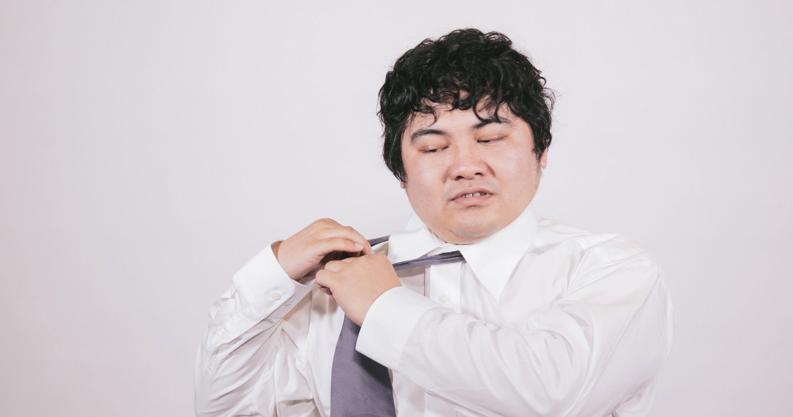 ネクタイを緩める疲れたサラリーマン［モデル：段田隼人］
