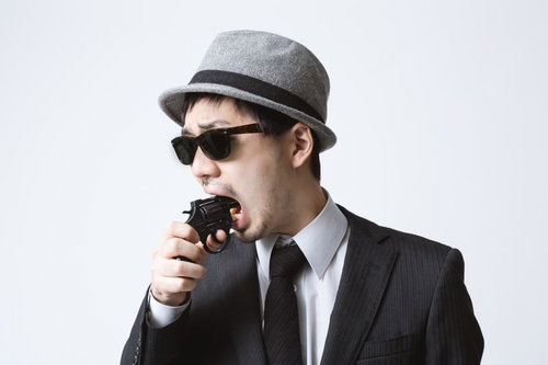 黒いスーツにサングラスで無線機を口元に持つエージェント風男性