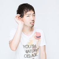 右手を耳に当てて聞き取る白Tシャツの男性の写真