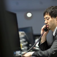 オフィスで受話器を耳に当てて電話するサラリーマンの写真