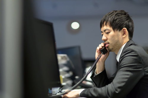 オフィスで受話器を耳に当てて電話するサラリーマン