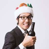 サンタ帽をかぶってワインボトルを持つスーツの男性の写真