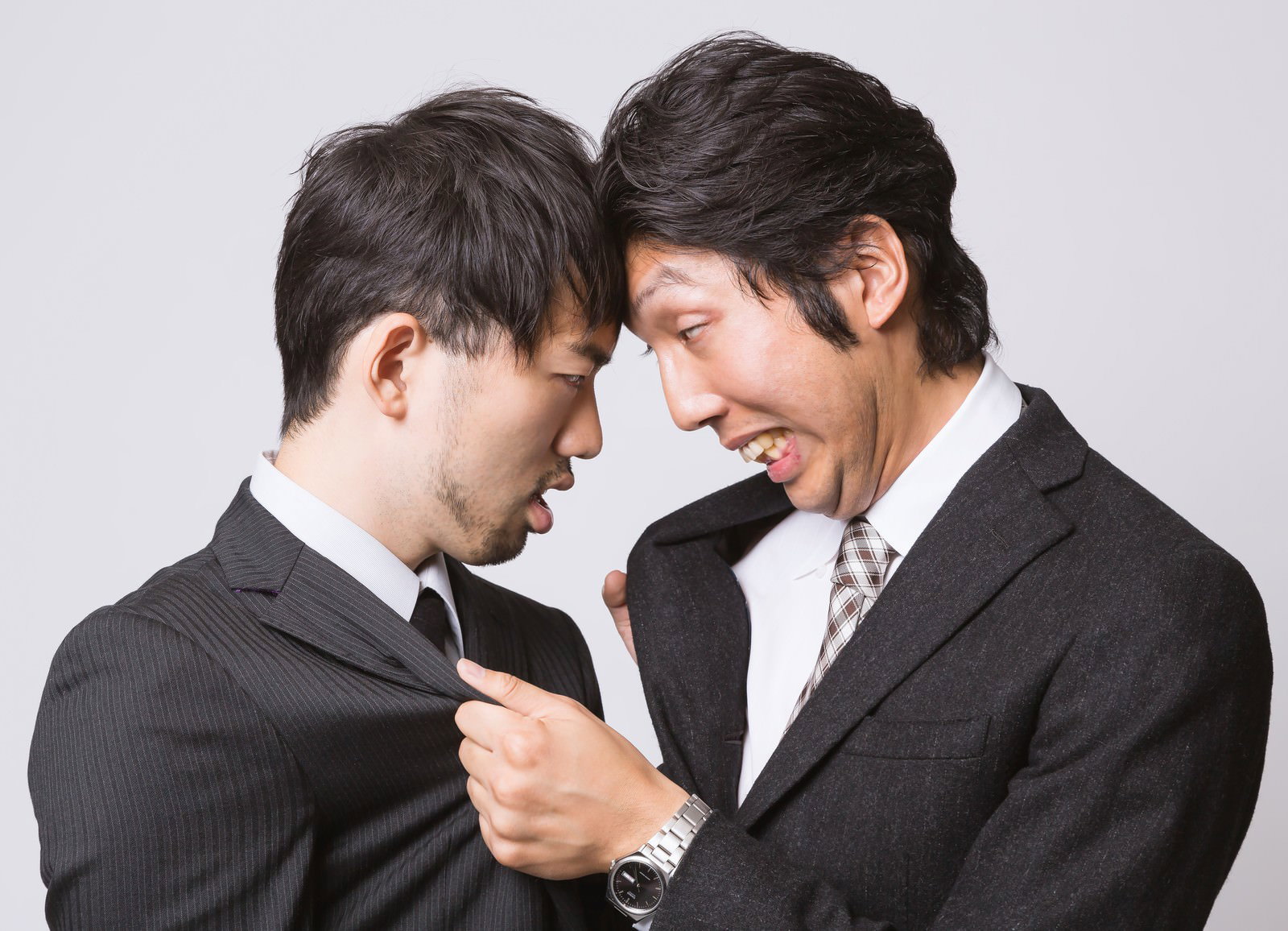 胸倉をつかみ合うスーツ姿の男性2人［モデル：ひろゆき  紳さん］