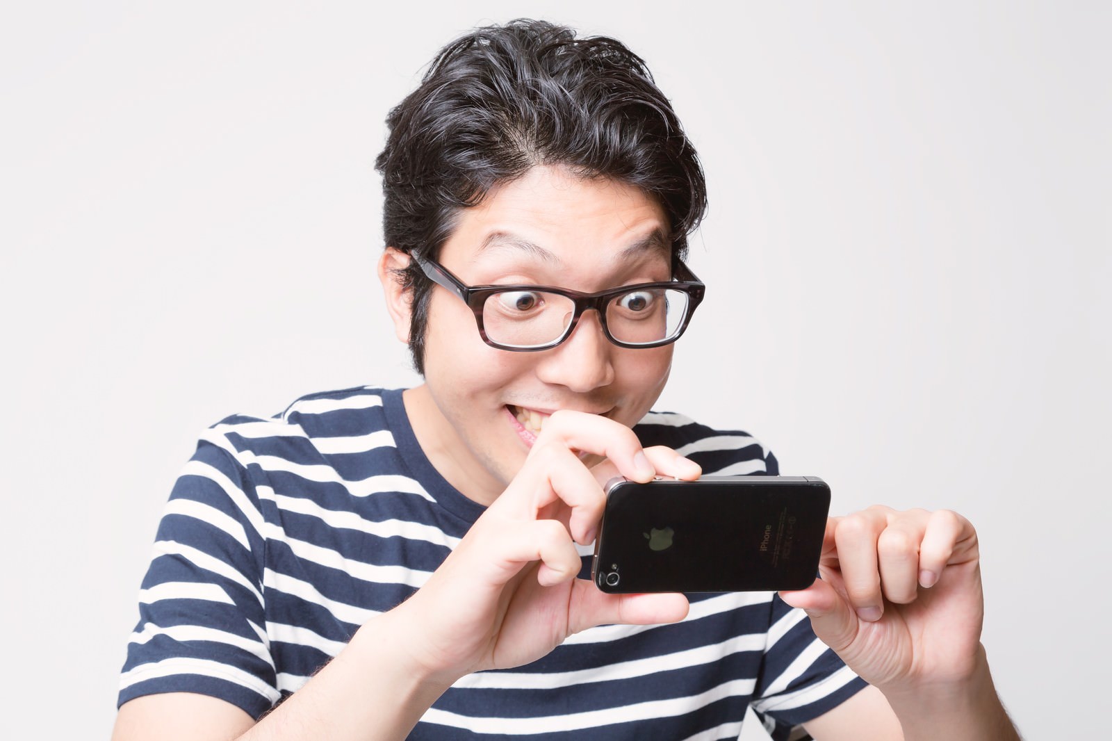 スマホで撮影する眼鏡をかけた紺白ストライプシャツの男性［モデル：紳さん］