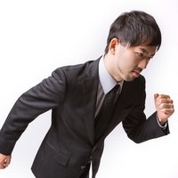 前のめりで走り出すサラリーマンの写真