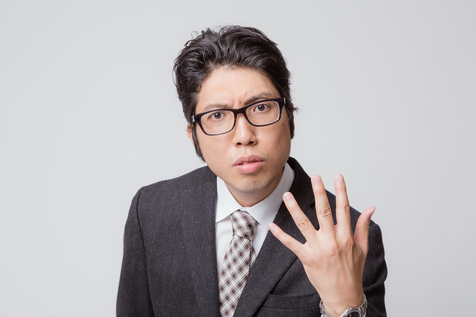 問い詰める表情の眼鏡姿のビジネスマン［モデル：紳さん］