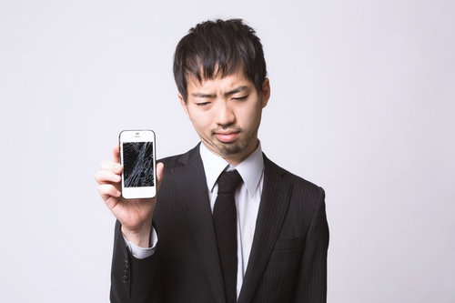 割れたスマホを見てガックリする男性