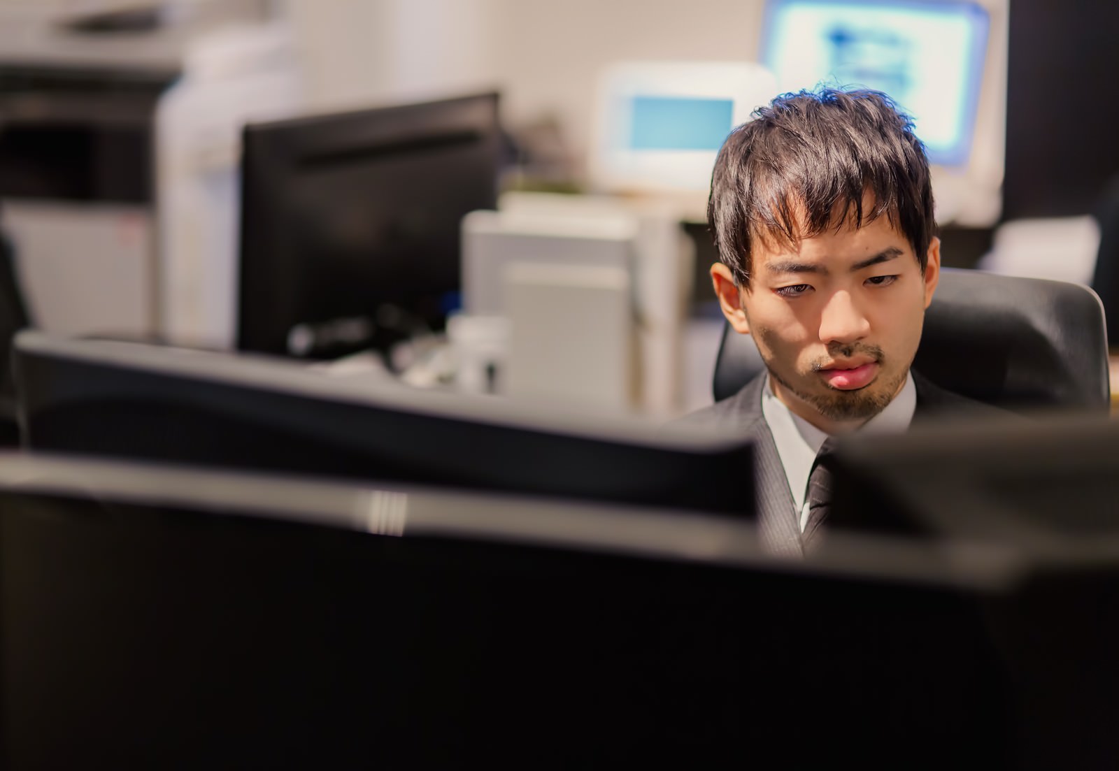 オフィスでモニター画面を見つめる男性スタッフ［モデル：ひろゆき］
