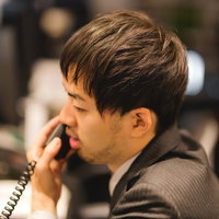 オフィスで受話器を耳に当てるビジネスマンの写真